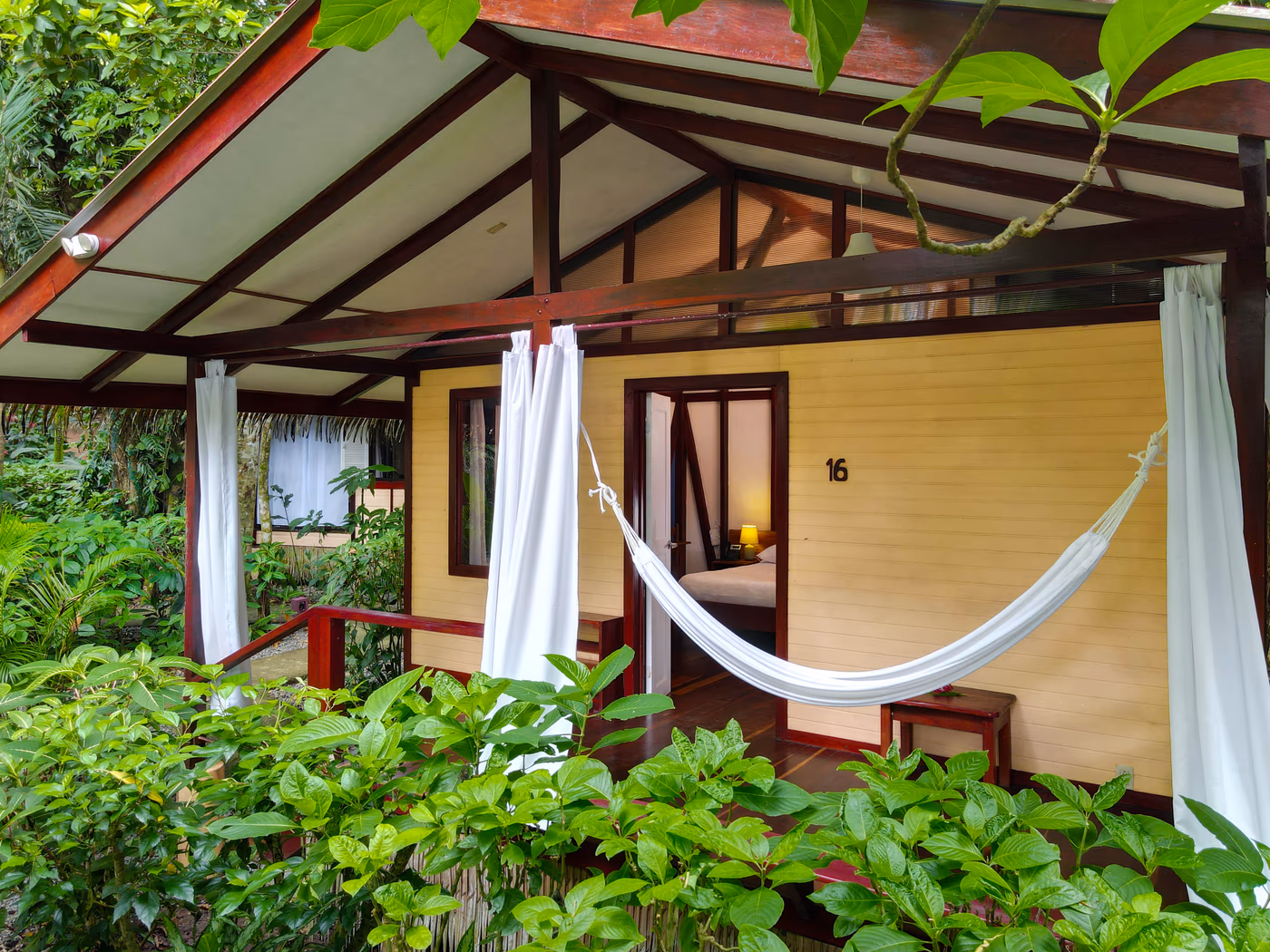 Deluxe Bungalow with hammock on the veranda, framed by tropical plants
